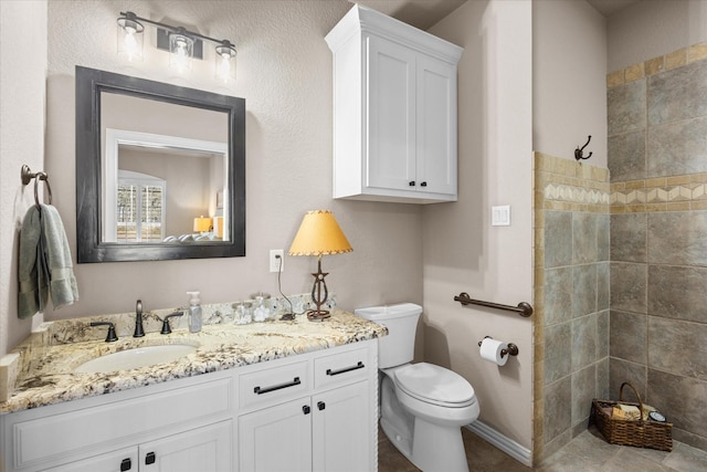 bathroom with toilet, vanity, and tiled shower