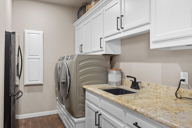 laundry room featuring washer and clothes dryer, sink, and cabinets