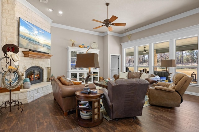 living room with ceiling fan, a stone fireplace, and ornamental molding