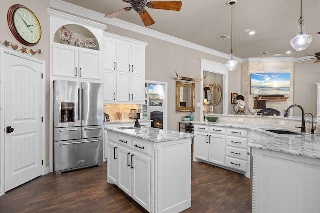 kitchen featuring stainless steel refrigerator with ice dispenser, white cabinets, a center island with sink, and sink