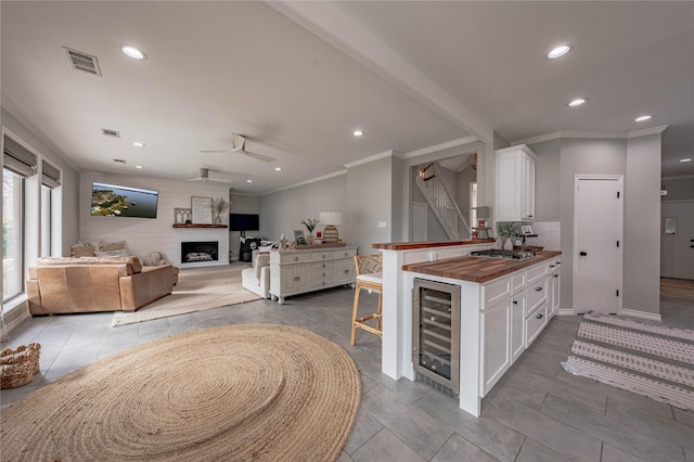 kitchen featuring wood counters, white cabinetry, beverage cooler, and a large fireplace