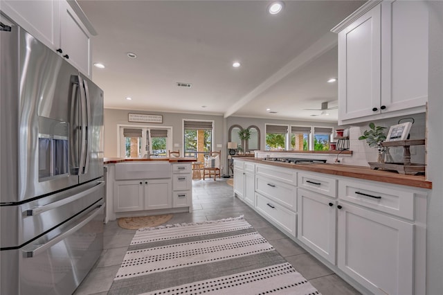 kitchen featuring kitchen peninsula, butcher block counters, appliances with stainless steel finishes, and white cabinetry