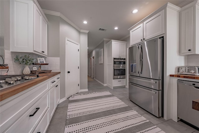 kitchen featuring white cabinets, stainless steel appliances, and wooden counters