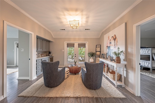 sitting room with dark wood-type flooring, ornamental molding, lofted ceiling, and french doors