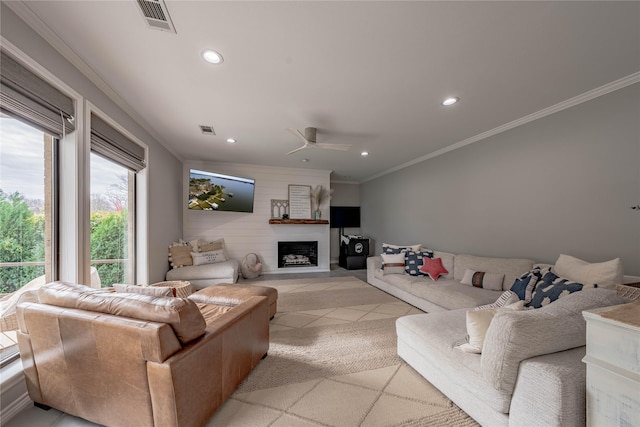 living room featuring ceiling fan, a fireplace, and crown molding