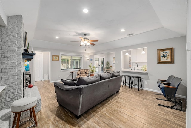 living room featuring ceiling fan, light wood-type flooring, and sink