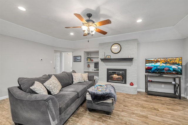 living room featuring ceiling fan, a fireplace, hardwood / wood-style floors, and built in shelves