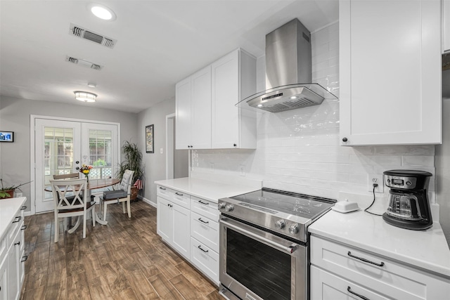 kitchen featuring wall chimney range hood, stainless steel electric range, white cabinets, french doors, and dark hardwood / wood-style flooring