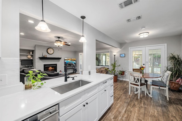 kitchen with a brick fireplace, pendant lighting, dishwasher, and sink