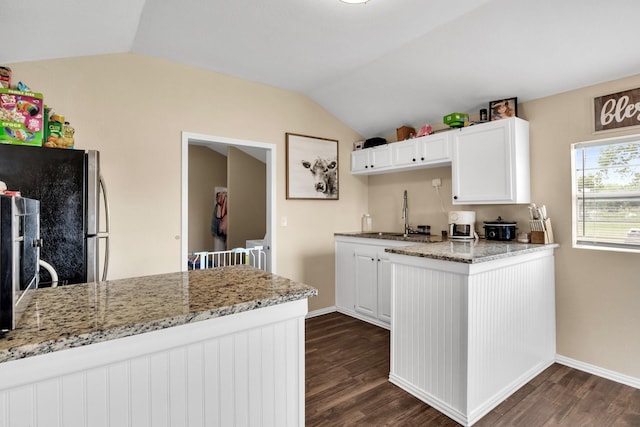 kitchen featuring dark wood-type flooring, light stone countertops, white cabinetry, and kitchen peninsula