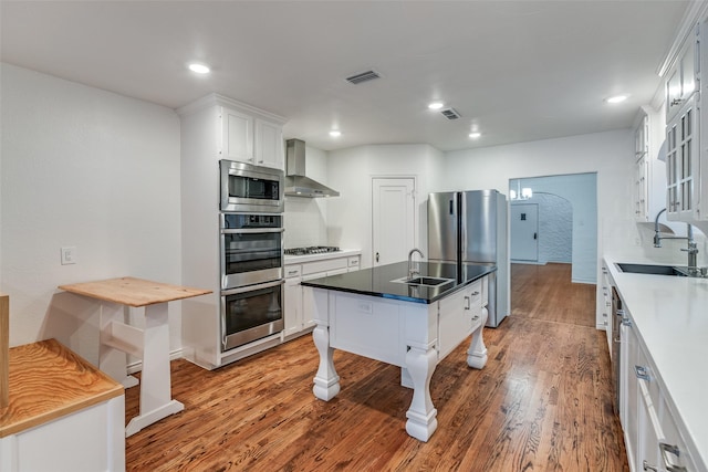 kitchen with white cabinetry, sink, and wall chimney range hood