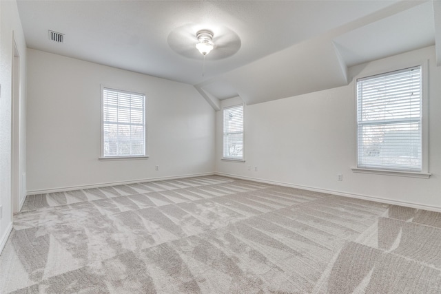 additional living space featuring light colored carpet and vaulted ceiling