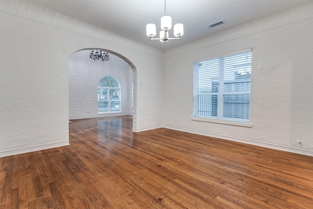 spare room with hardwood / wood-style floors and an inviting chandelier