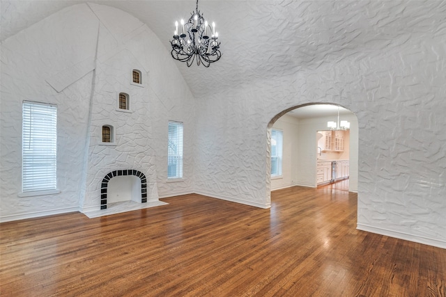 unfurnished living room with vaulted ceiling, hardwood / wood-style floors, a stone fireplace, and sink