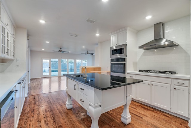 kitchen with white cabinets, backsplash, wall chimney range hood, and stainless steel appliances