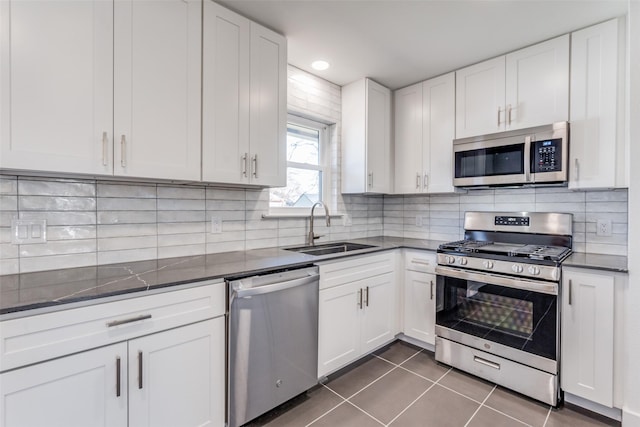 kitchen featuring sink, white cabinetry, dark tile patterned floors, and stainless steel appliances