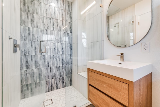 bathroom with a tile shower and vanity