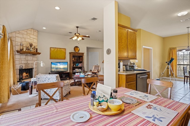 dining room featuring vaulted ceiling, ceiling fan, light tile patterned flooring, and a fireplace