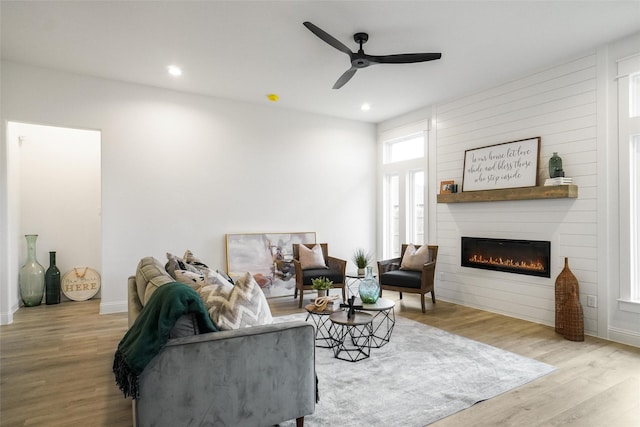 living room with a fireplace, light hardwood / wood-style floors, and ceiling fan