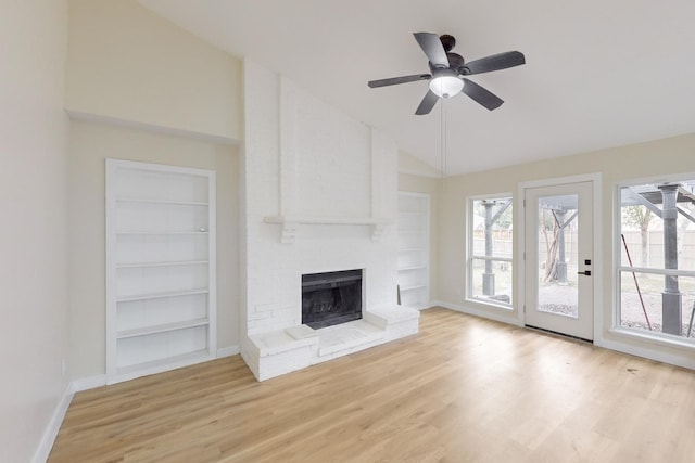 unfurnished living room with lofted ceiling, light hardwood / wood-style flooring, built in features, ceiling fan, and a fireplace