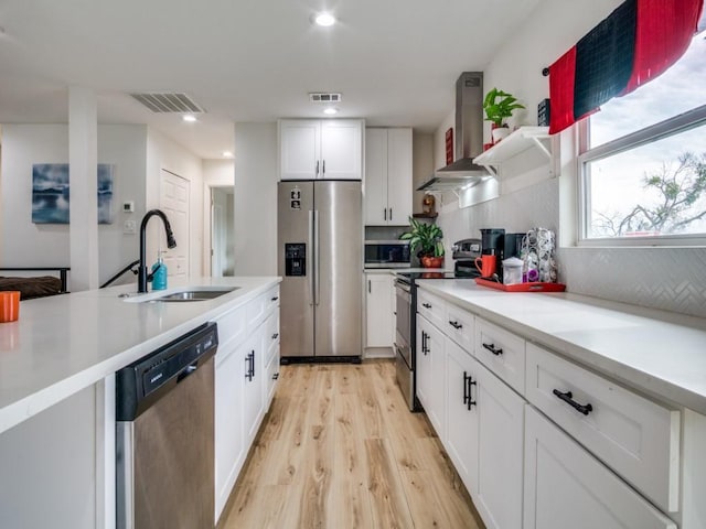 kitchen featuring exhaust hood, white cabinetry, stainless steel appliances, decorative backsplash, and sink