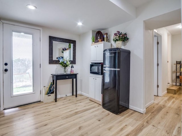 kitchen with light wood-type flooring, white cabinetry, plenty of natural light, and black appliances