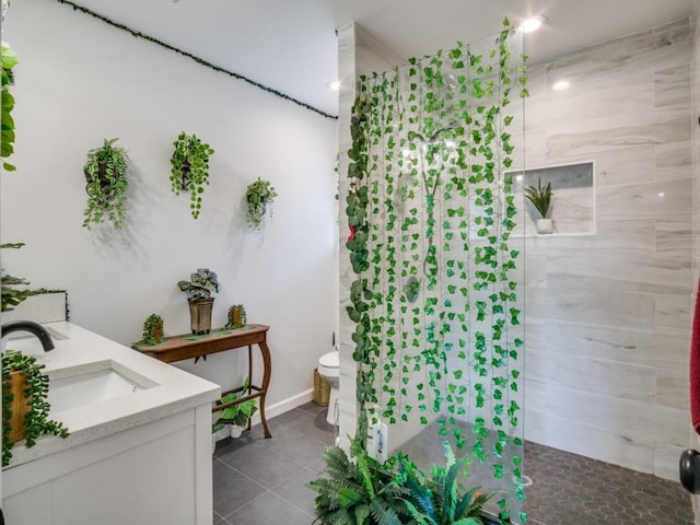 bathroom with toilet, vanity, tile patterned flooring, and a shower