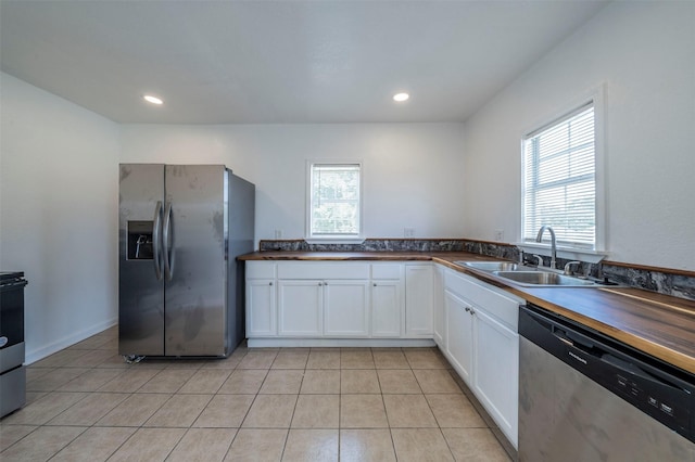 kitchen with a healthy amount of sunlight, sink, stainless steel appliances, and white cabinetry