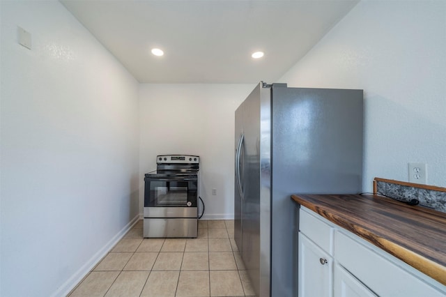 kitchen featuring light tile patterned flooring, appliances with stainless steel finishes, white cabinets, and butcher block countertops