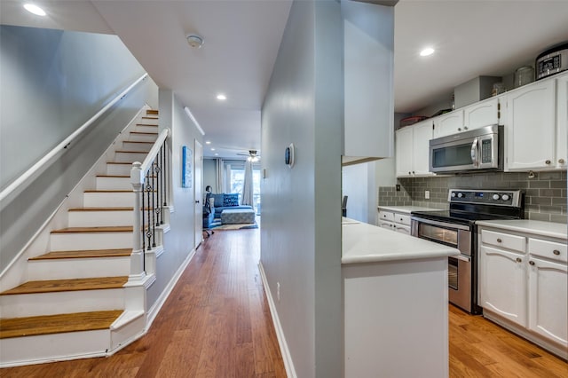 kitchen featuring ceiling fan, light hardwood / wood-style floors, white cabinetry, and stainless steel appliances