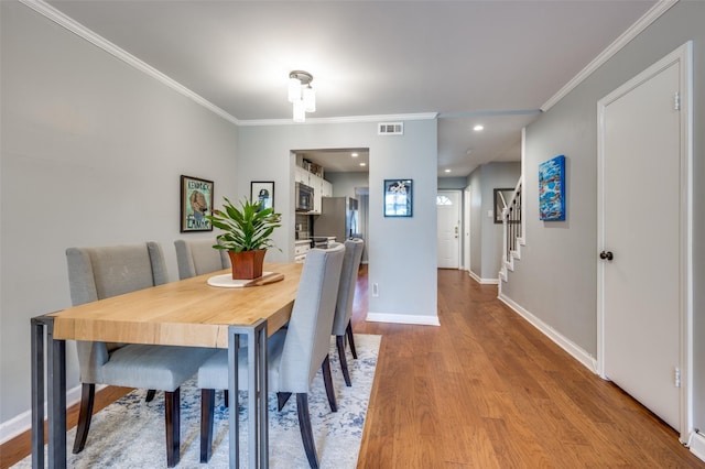 dining area with light hardwood / wood-style flooring and crown molding