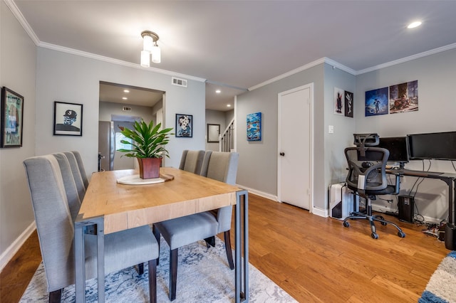 dining area featuring wood-type flooring and ornamental molding