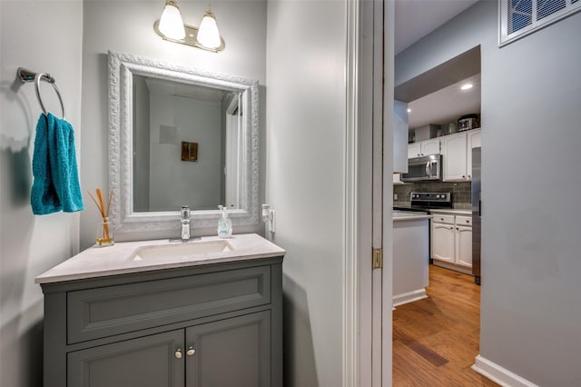 bathroom with vanity, backsplash, and hardwood / wood-style floors