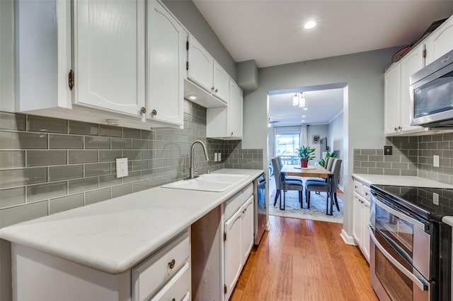 kitchen with white cabinetry, stainless steel appliances, backsplash, light wood-type flooring, and sink