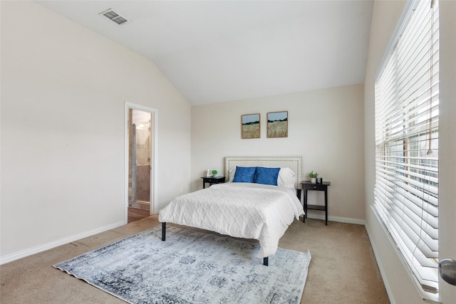 bedroom with light carpet, vaulted ceiling, and ensuite bath