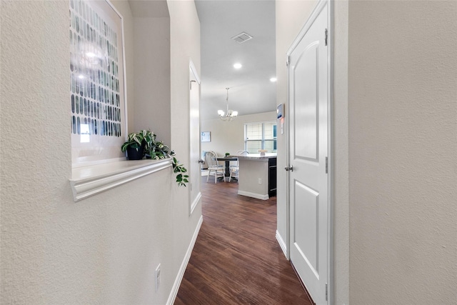 hallway with dark hardwood / wood-style floors and a notable chandelier