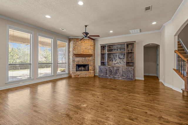 unfurnished living room featuring ceiling fan, plenty of natural light, a textured ceiling, and a fireplace