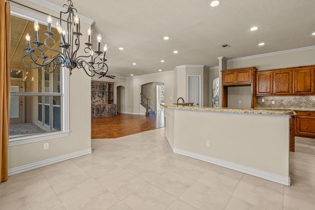 kitchen featuring ceiling fan with notable chandelier, light stone countertops, light tile patterned floors, and ornamental molding