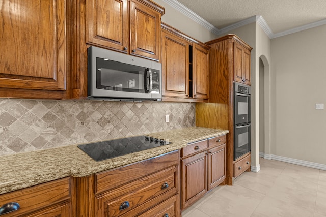 kitchen featuring decorative backsplash, light stone countertops, appliances with stainless steel finishes, ornamental molding, and a textured ceiling