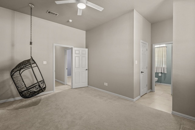 interior space with ceiling fan, a towering ceiling, light colored carpet, and ensuite bath