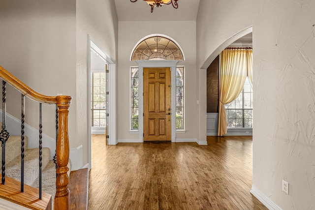 foyer entrance with a wealth of natural light, a notable chandelier, and hardwood / wood-style floors