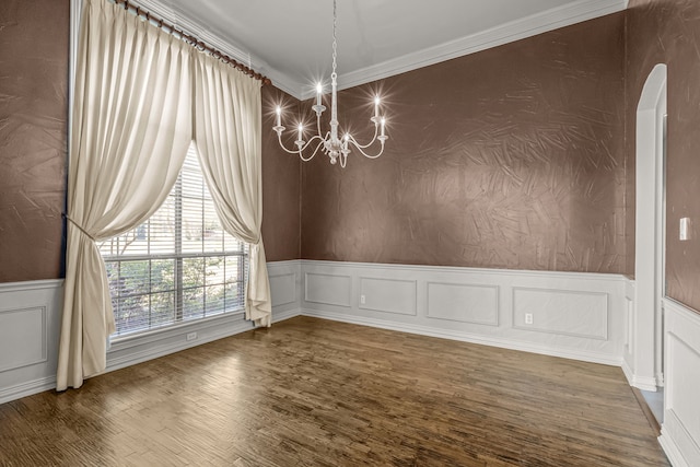 spare room featuring a notable chandelier, crown molding, and hardwood / wood-style flooring