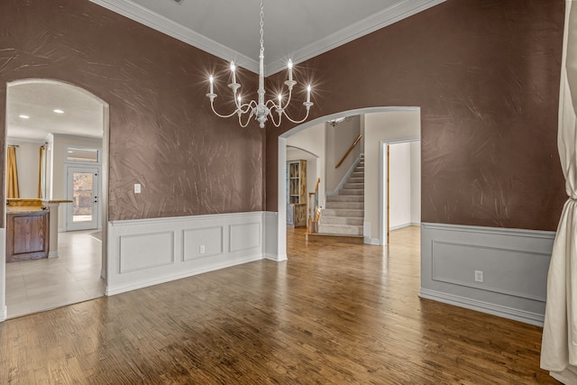 spare room with a chandelier, wood-type flooring, and ornamental molding