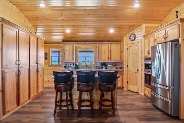 kitchen featuring stainless steel refrigerator with ice dispenser, light brown cabinetry, lofted ceiling, and a kitchen island