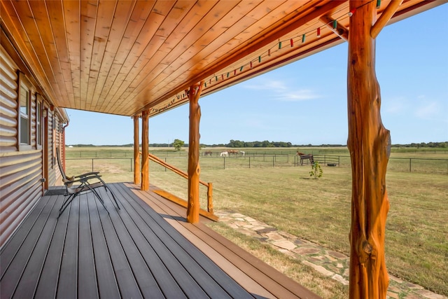 wooden terrace with a rural view and a lawn