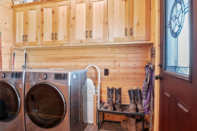 clothes washing area featuring log walls, washer and dryer, and cabinets