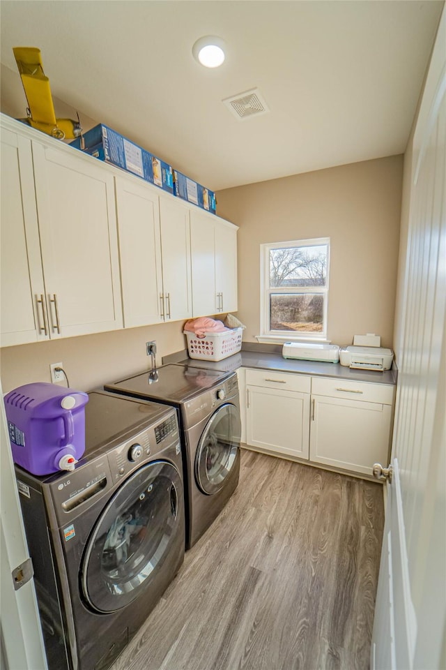 laundry room with cabinets, light hardwood / wood-style flooring, and washing machine and dryer