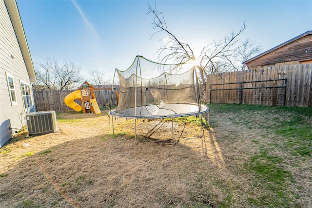 view of yard featuring a playground, central AC, and a trampoline