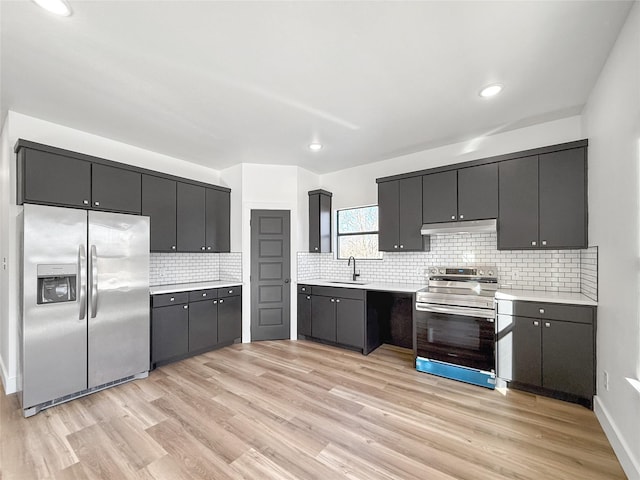 kitchen featuring stainless steel appliances, light hardwood / wood-style floors, backsplash, and sink