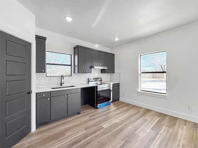 kitchen with sink, backsplash, light hardwood / wood-style flooring, and stainless steel electric range